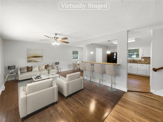 living room with a textured ceiling, dark hardwood / wood-style flooring, and plenty of natural light