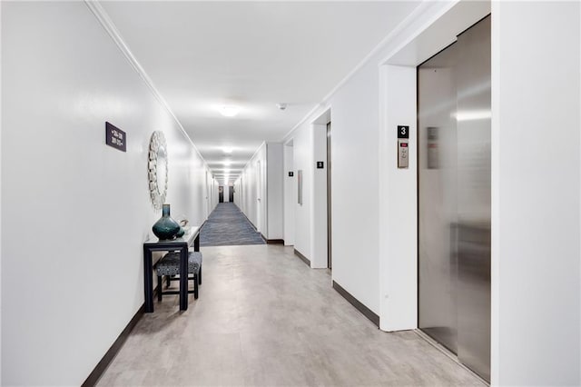 hall with elevator, ornamental molding, and concrete flooring