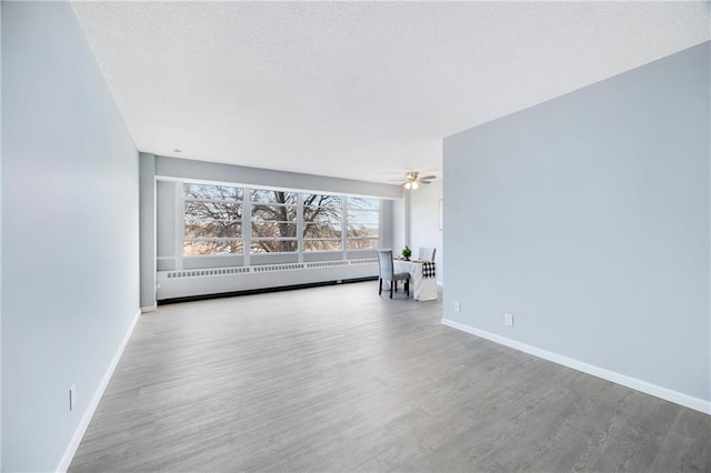 spare room with hardwood / wood-style floors, a baseboard radiator, radiator heating unit, and ceiling fan