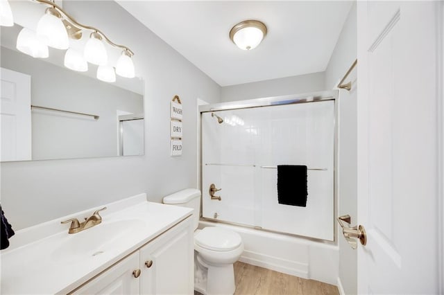 full bathroom featuring vanity, hardwood / wood-style flooring, toilet, and combined bath / shower with glass door