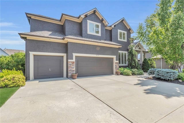 view of front of house featuring driveway, stone siding, a garage, and stucco siding