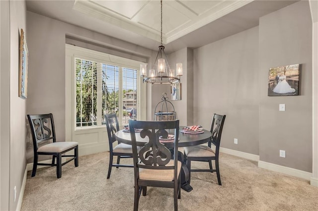 dining area featuring a chandelier, a raised ceiling, light colored carpet, and baseboards