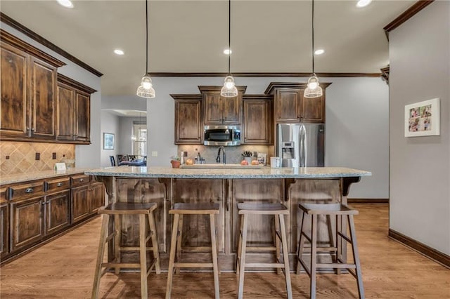 kitchen with light stone counters, dark brown cabinetry, stainless steel appliances, light wood finished floors, and crown molding