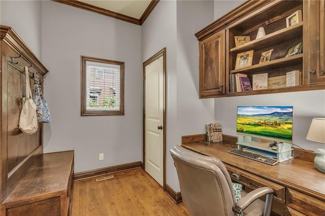 home office featuring baseboards, light wood-style floors, built in desk, and crown molding