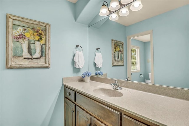 bathroom featuring vanity, toilet, and an inviting chandelier