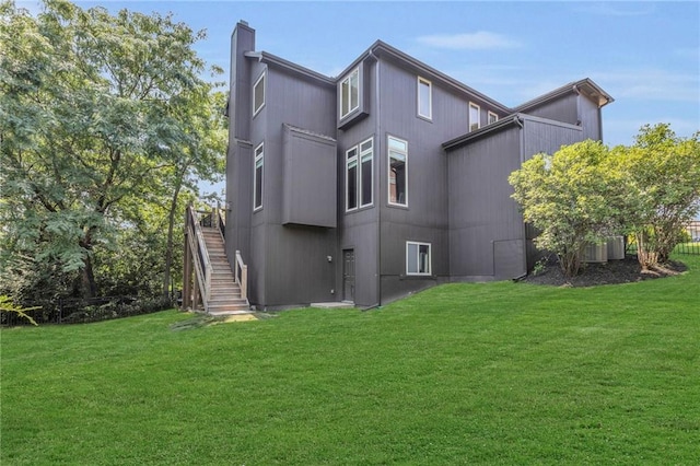 back of property with central AC, a yard, stairway, and a chimney