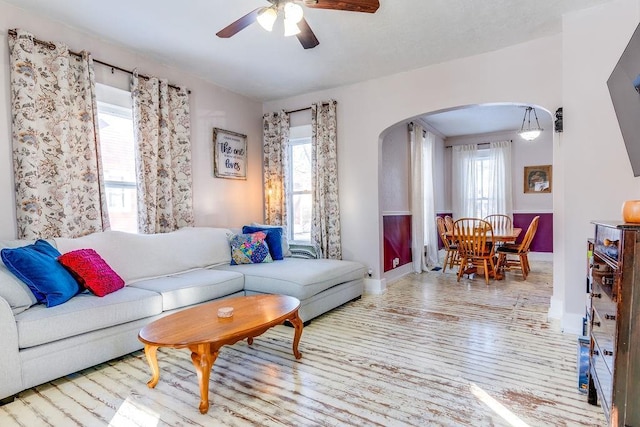 living room with light wood-type flooring, ceiling fan, and a healthy amount of sunlight