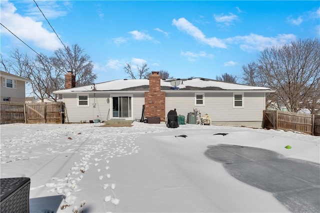 snow covered property featuring a chimney and fence