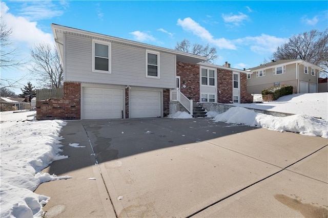 split foyer home with driveway, an attached garage, and brick siding