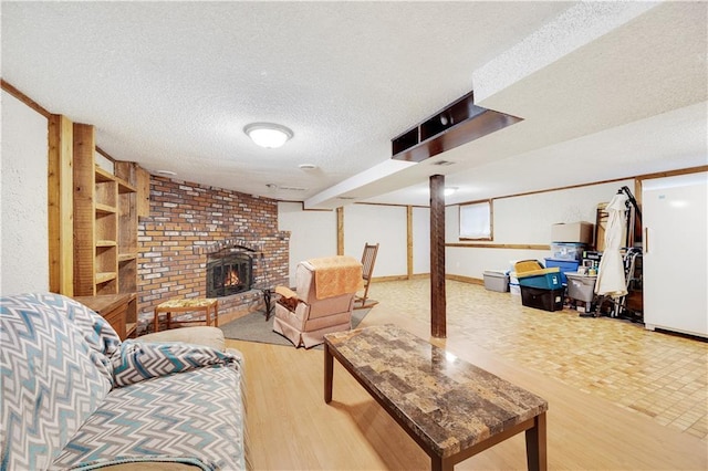 living room featuring a brick fireplace, a textured ceiling, and wood finished floors