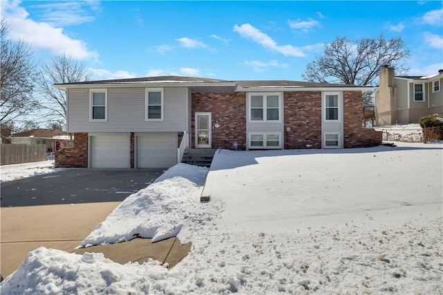 bi-level home with an attached garage, aphalt driveway, and brick siding