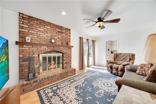 living room with light wood finished floors, ceiling fan, a fireplace, and recessed lighting