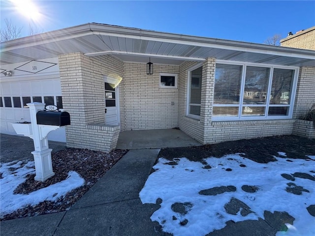 snow covered property entrance featuring a garage