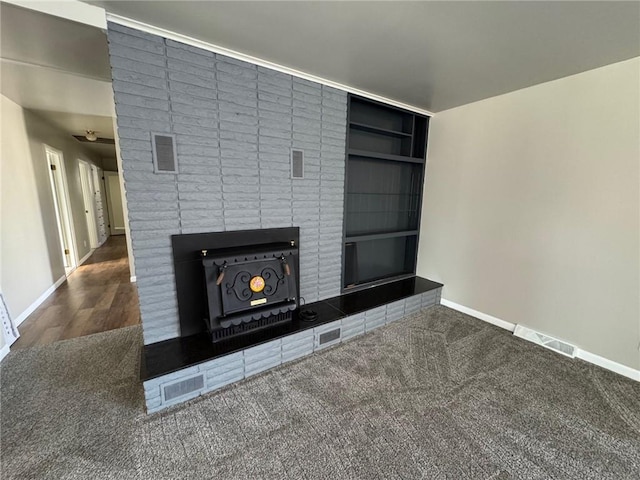 unfurnished living room featuring dark colored carpet and built in features