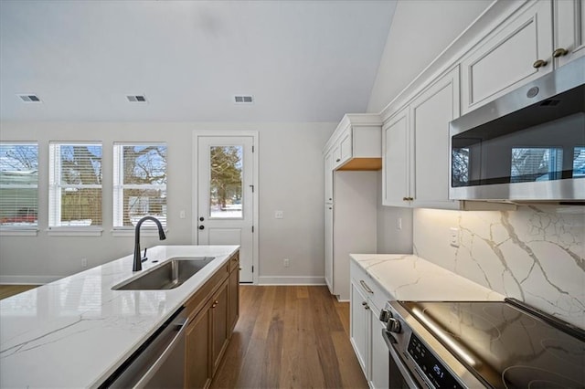 kitchen with white cabinets, appliances with stainless steel finishes, sink, backsplash, and light stone counters