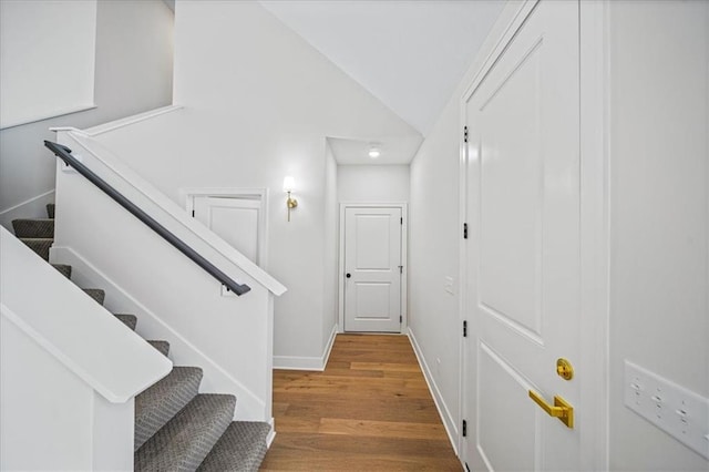 stairs featuring vaulted ceiling and wood-type flooring