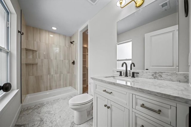 bathroom featuring toilet, a tile shower, and vanity