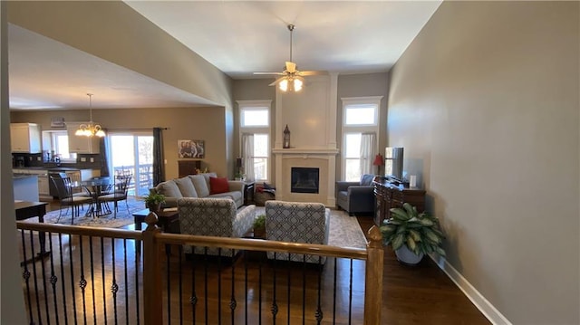 living room featuring ceiling fan with notable chandelier and hardwood / wood-style flooring