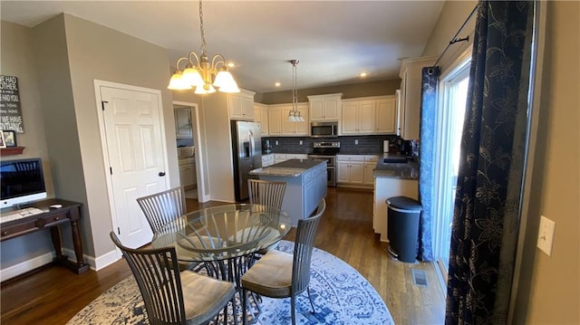 dining room with dark wood-type flooring, an inviting chandelier, and sink