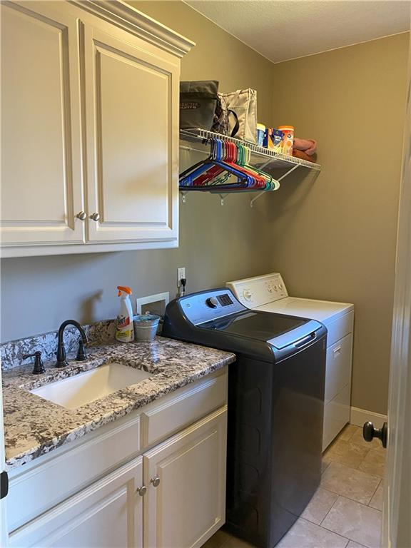 washroom with cabinets, sink, and independent washer and dryer