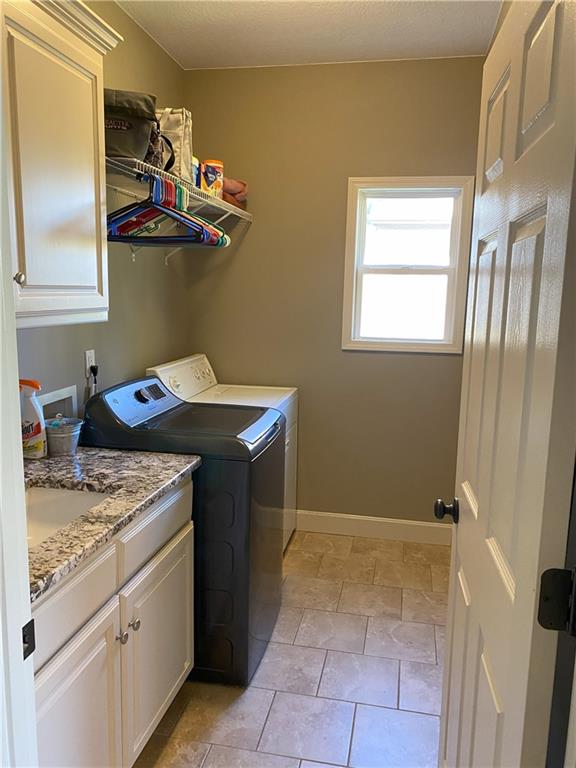 laundry area featuring cabinets, separate washer and dryer, and light tile patterned flooring