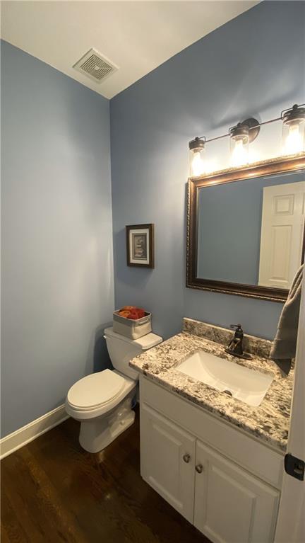 bathroom featuring toilet, vanity, and hardwood / wood-style floors