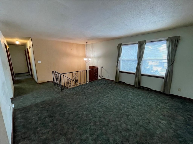 carpeted empty room with a textured ceiling and an inviting chandelier