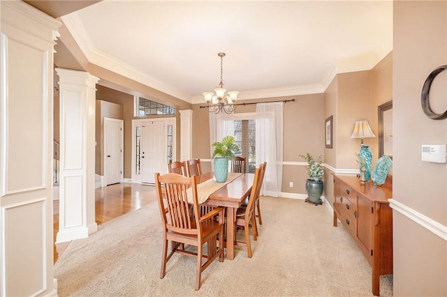 carpeted dining room with an inviting chandelier, ornamental molding, and ornate columns