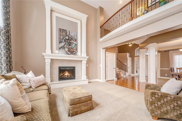 carpeted living room with ornate columns and a towering ceiling