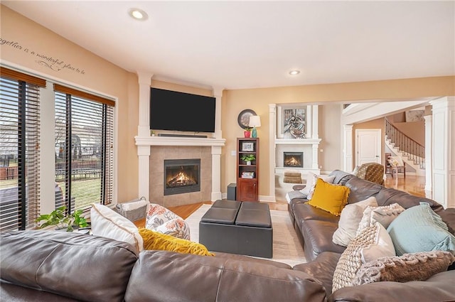 living room with a fireplace, light wood-type flooring, and ornate columns