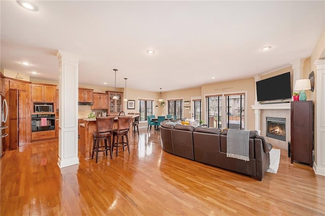 living room with ornate columns and light hardwood / wood-style floors