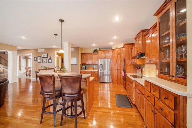 kitchen featuring a kitchen bar, decorative columns, black appliances, a kitchen island, and decorative light fixtures