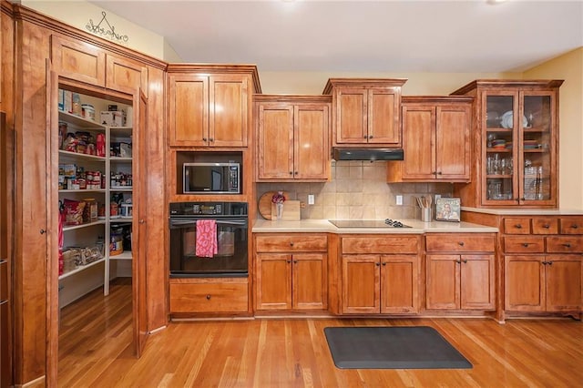 kitchen with decorative backsplash, light hardwood / wood-style flooring, and black appliances