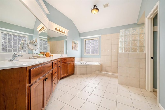 bathroom featuring tile patterned floors, vaulted ceiling, vanity, and tiled tub