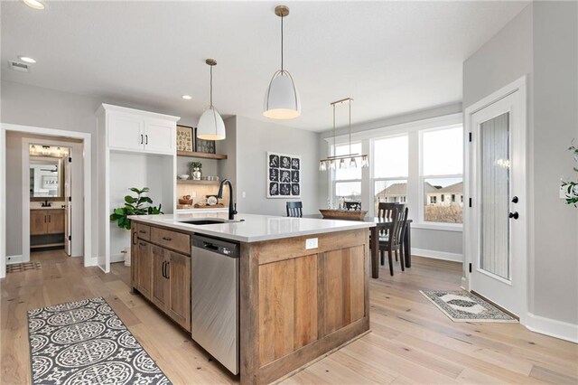 kitchen with white cabinetry, a center island with sink, light wood-type flooring, sink, and stainless steel dishwasher