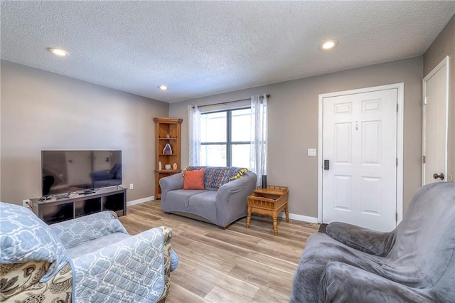 living room with a textured ceiling and light wood-type flooring