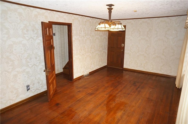 empty room with dark wood-type flooring, crown molding, and a textured ceiling