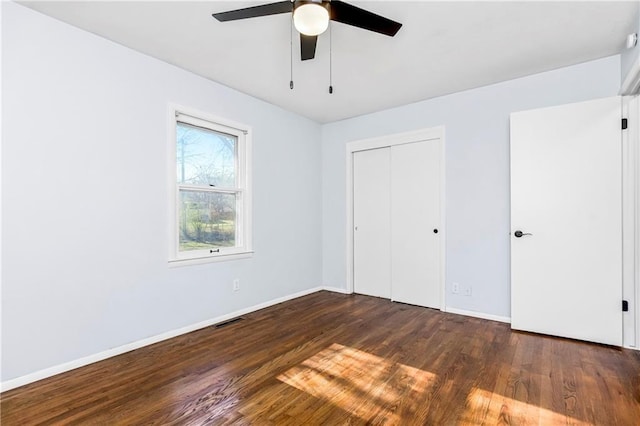 unfurnished bedroom featuring ceiling fan, a closet, and dark wood-type flooring