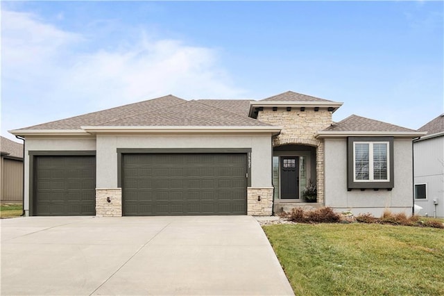 prairie-style home with driveway, stone siding, an attached garage, a front lawn, and stucco siding