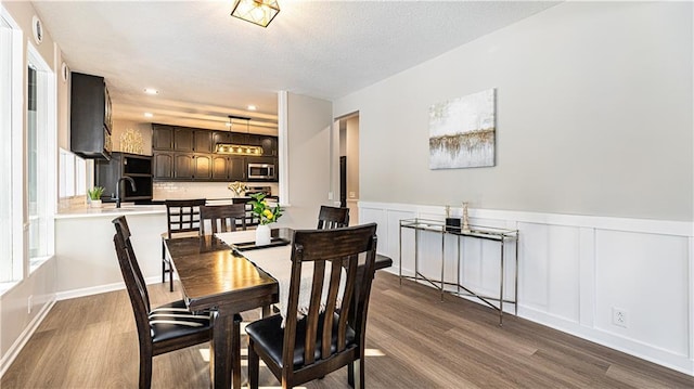 dining room with sink, hardwood / wood-style floors, and a textured ceiling