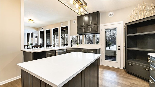 kitchen with dark brown cabinetry, a kitchen island, light hardwood / wood-style floors, sink, and stainless steel dishwasher