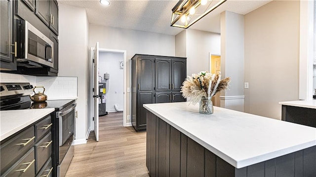 kitchen with a center island, light hardwood / wood-style floors, decorative backsplash, a textured ceiling, and stainless steel appliances