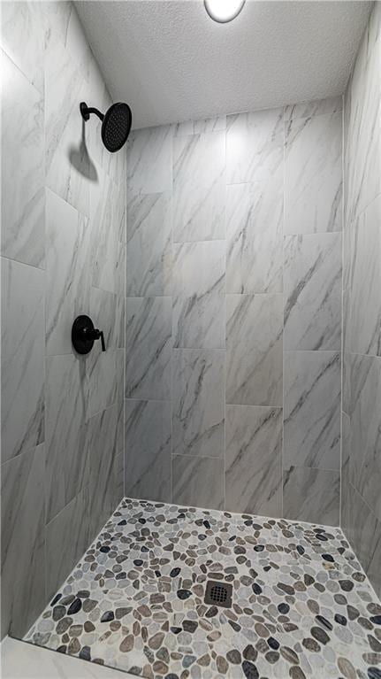 bathroom with a textured ceiling and tiled shower