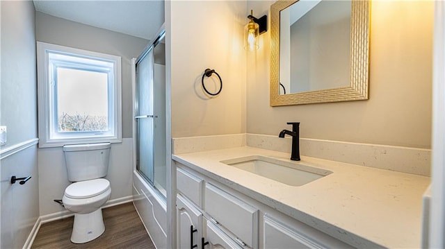 full bathroom with toilet, bath / shower combo with glass door, wood-type flooring, and vanity