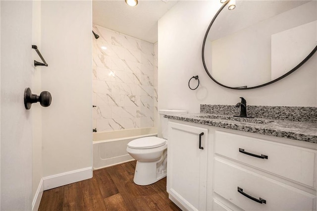 bathroom featuring wood finished floors, vanity, toilet, baseboards, and washtub / shower combination