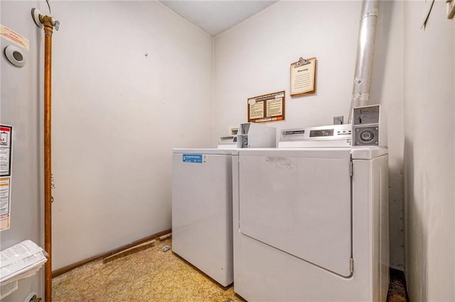 community laundry room featuring separate washer and dryer, water heater, and light floors