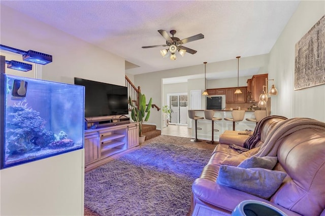 living room featuring ceiling fan, carpet floors, and a textured ceiling