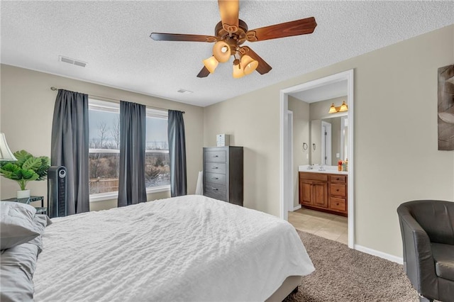 carpeted bedroom with ceiling fan, ensuite bathroom, and a textured ceiling