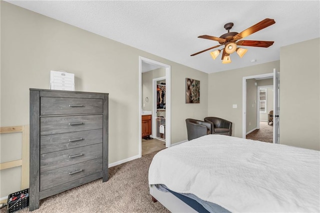 carpeted bedroom with ensuite bathroom, a walk in closet, and ceiling fan