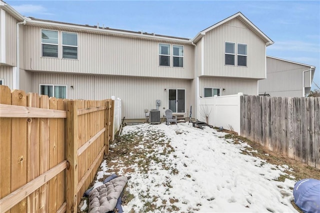 snow covered back of property featuring central AC